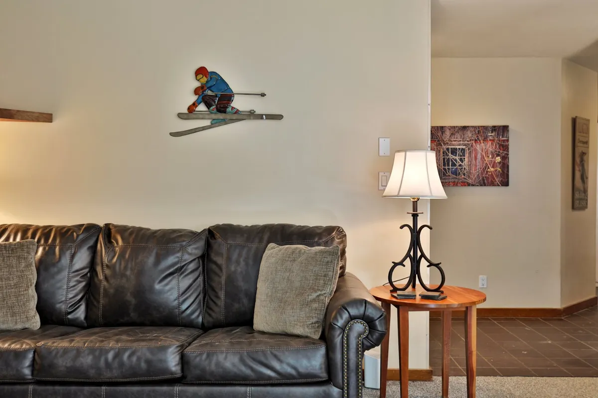 A cozy living area with a leather sofa, skiing decor, and a glowing table lamp. The inviting mood suggests relaxation and intimate moments after a day of adventure.