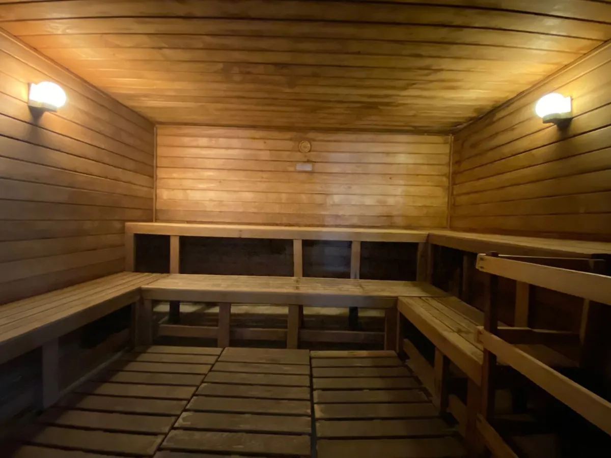 A calming interior photo of the sauna, with wooden benches and soft lighting, inviting moments of wellness and self-care rituals.