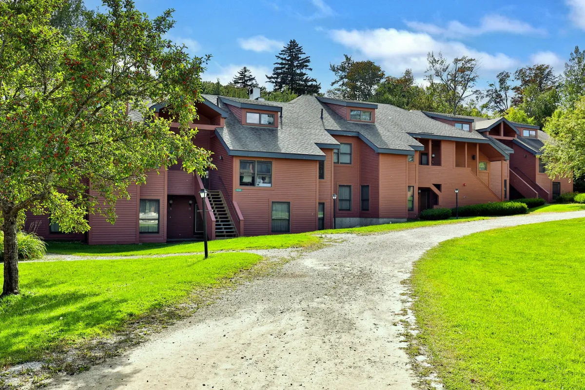 A welcoming view of the building structure with surrounding greenery and a winding pathway, inviting residents and guests to explore the area, gather outdoors, or take a leisurely stroll.