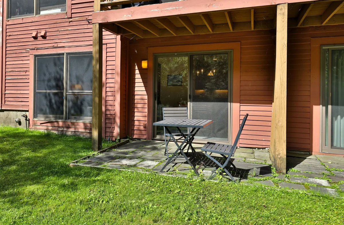 An exterior patio area with a table and chairs, sliding glass door, and green grass. The scene suggests a relaxed setting to gather before heading out or to unwind after exploring local attractions, blurring the lines between indoor comfort and the outdoors.