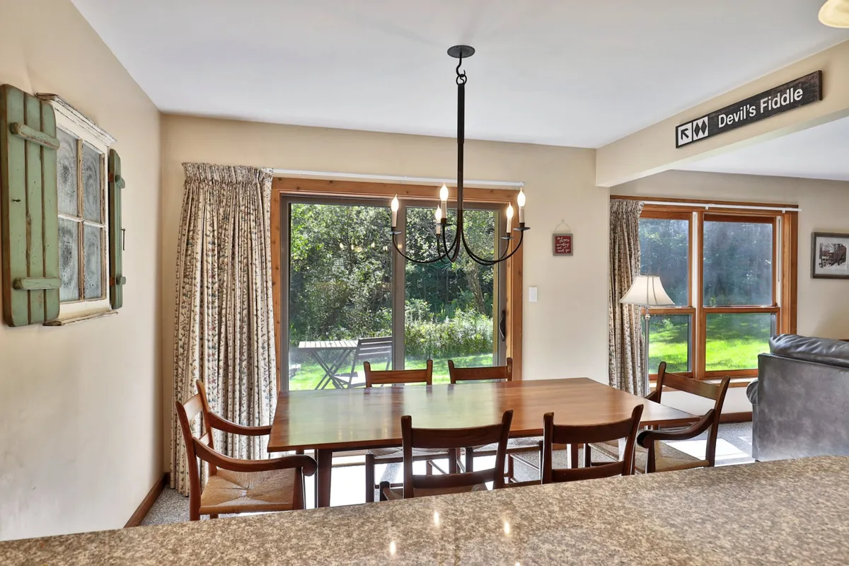 A spacious dining area with a large table situated near a window, allowing natural light to fill the room. The table is set for gatherings, and the ambiance is both inviting and festive, ideal for shared meals after a day outdoors.