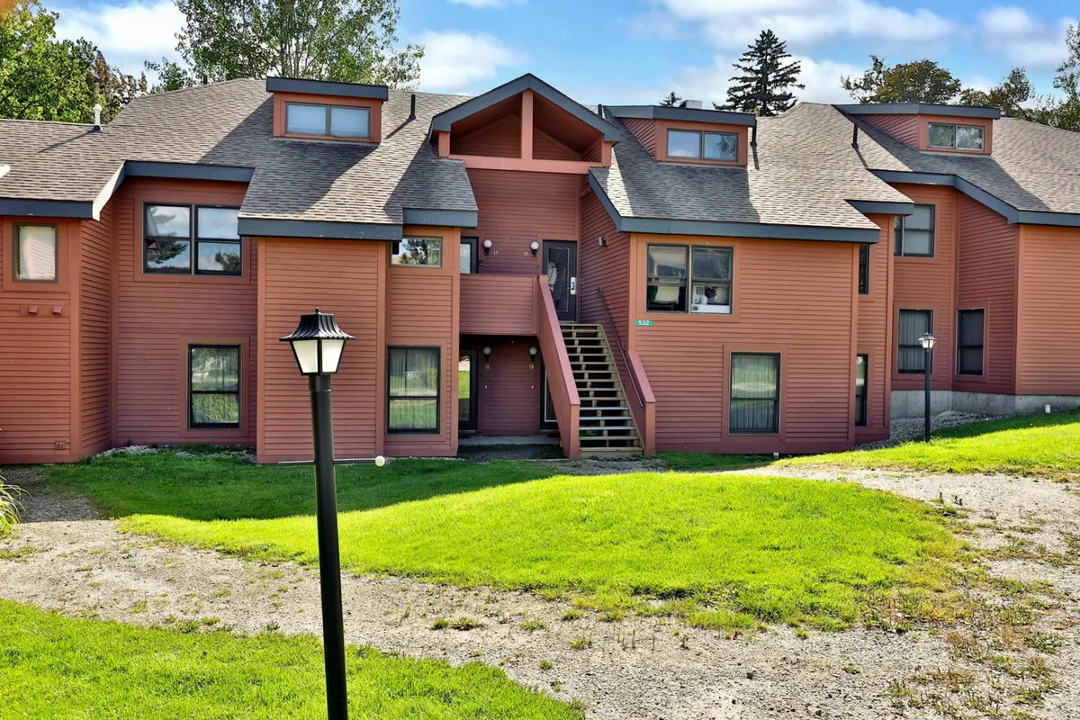 The exterior view of Trail Creek showcases colorful siding, a welcoming staircase, manicured lawns, and a classic lamp post, creating a charming and approachable first impression. The landscaped yard hints at outdoor play and community activities.